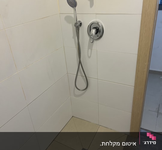 מקלחת עם ראש מקלחת על קיר אריחים